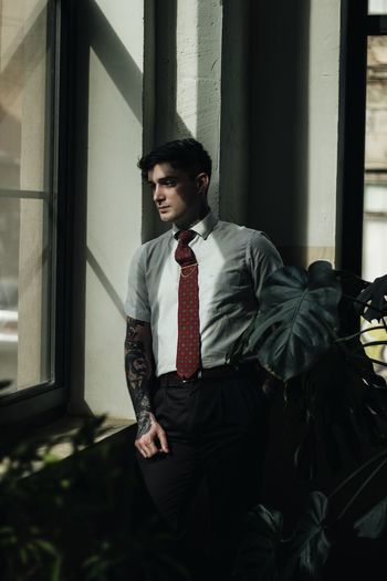 Thoughtful young man looking through window