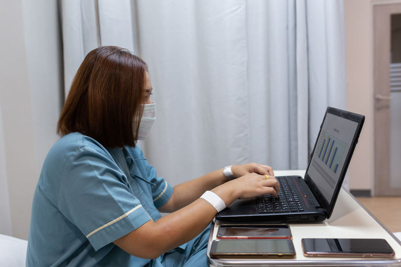 Illness asian patient women still  using laptop for working hard  in patient room of hospital