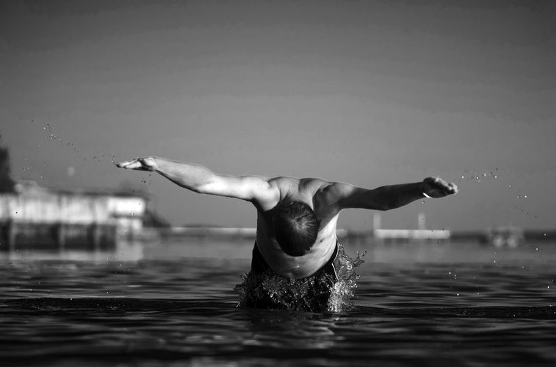 Rear view of swimming the butterfly stroke outdoors