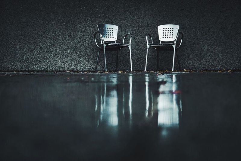 Close-up of empty chairs on table against wall