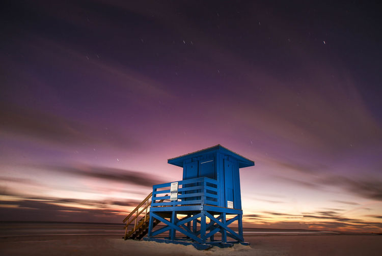 Lifeguard hut by sea against sky at night