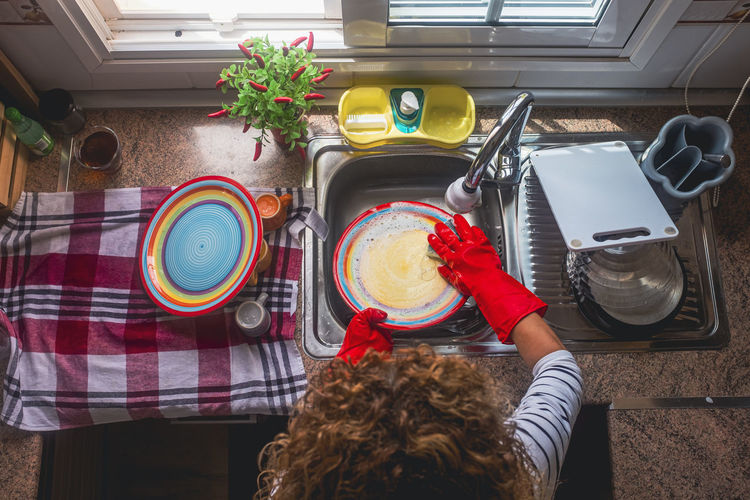 Curly haired woman cleaning dishes at home