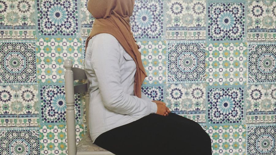 Low section of woman sitting against tiled wall