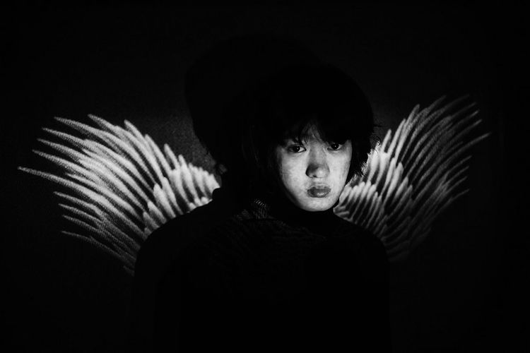 Portrait of woman with wings in darkroom