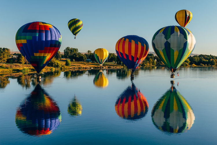 Multi colored hot air balloon flying over water
