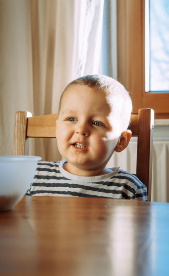 Portrait of cute boy sitting on table at home