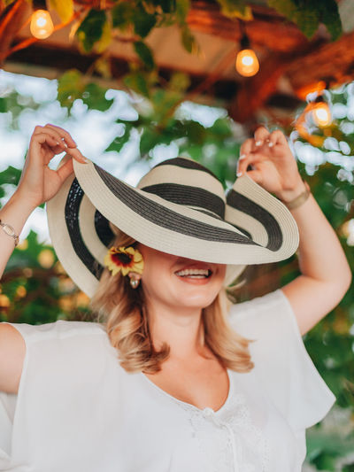 Close-up of smiling woman wearing hat standing outdoors