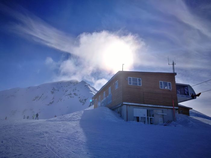 Building by snowcapped mountain against sky