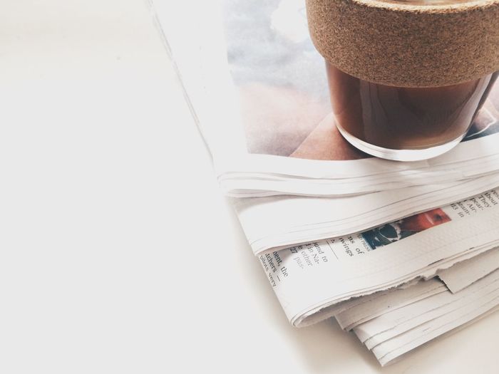 High angle view of black coffee over newspaper on table