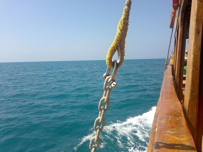 Chain hanging on boat over sea against clear sky