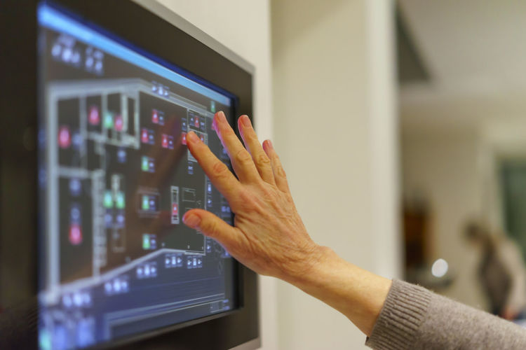 Senior woman's hand touching display panel of domestic technology