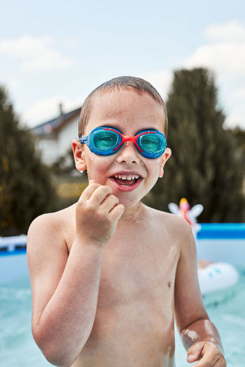 Portrait of happy smiling boy playing in a pool having fun on a summer sunny day