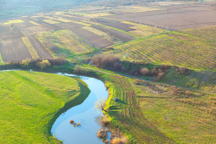 Top view of flowing river with fields and gardens . spring rustic panorama