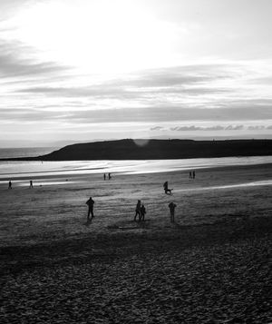 People playing on beach against sky