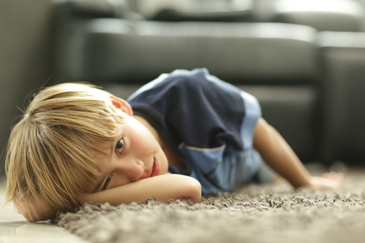 Portrait of boy lying on rug at home