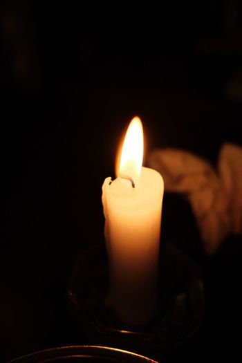 Close-up of lit candle in darkroom