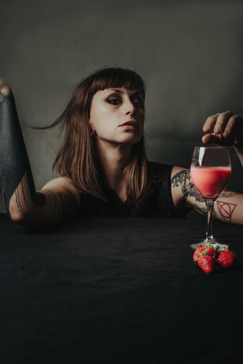 Portrait of young woman with drink on table