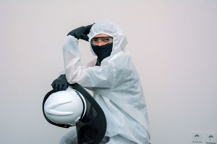 Portrait of man wearing protective suit against white background
