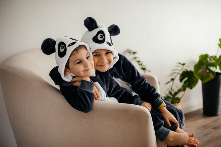 Portrait of sibling sitting on sofa at home