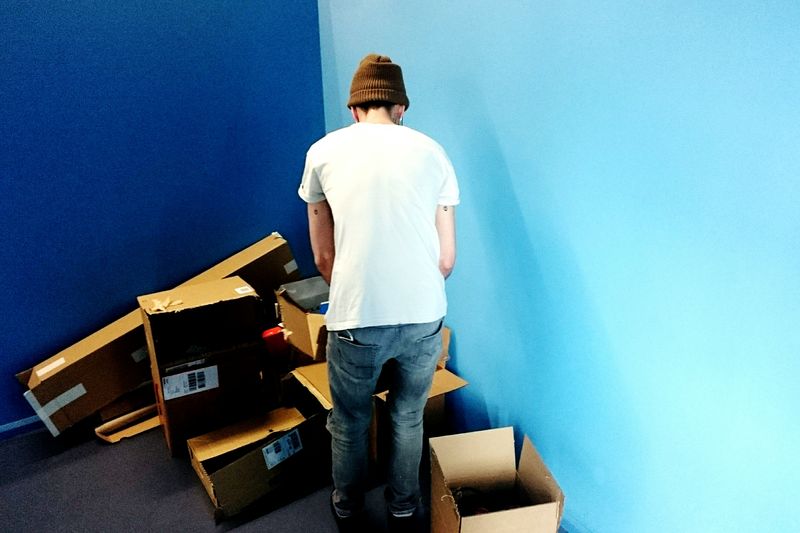 Rear view of man with cardboard boxes in room