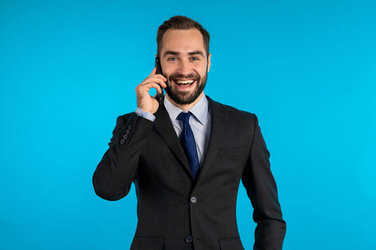 Portrait of smiling man standing against blue background