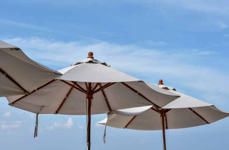 White canvas beach parasols.low angle view shot against light blue sky and clouds.