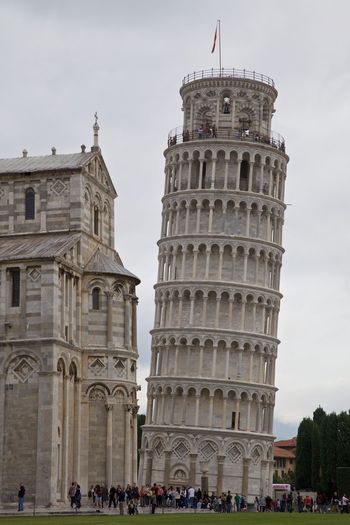 People in front of leaning tower of pisa against sky