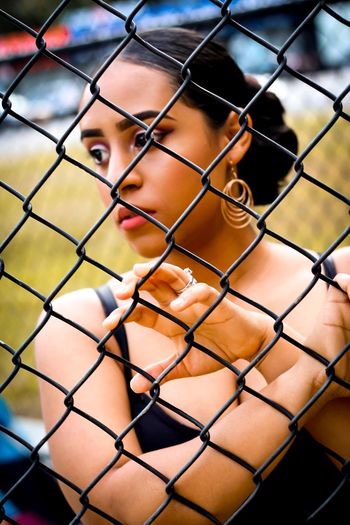 Close-up of woman seen through chainlink fence
