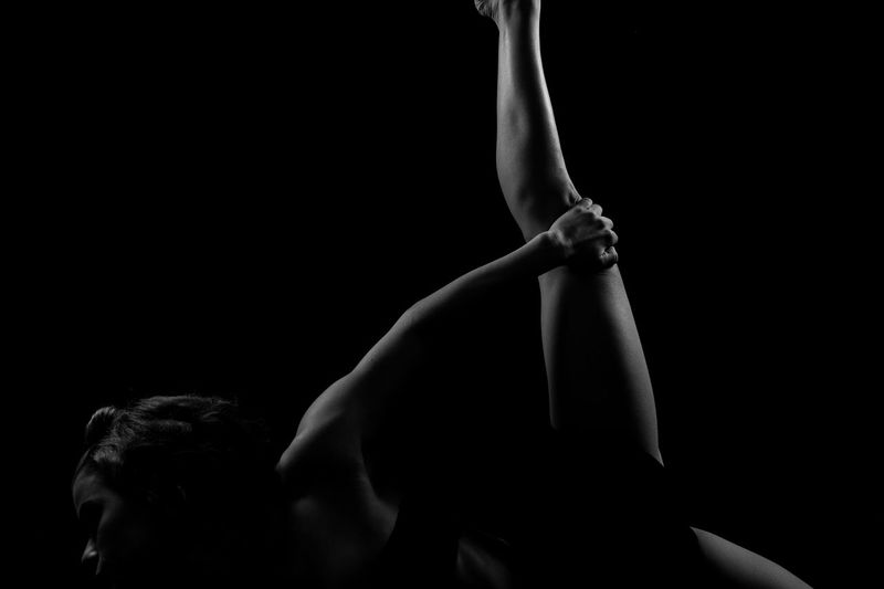 Athlete stretching against black background