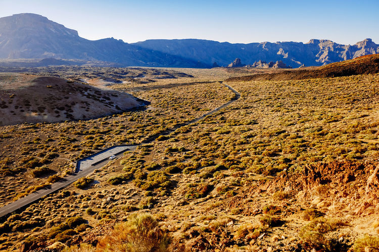 A mountain road crosses a spectacular valley at noon near mount teide.