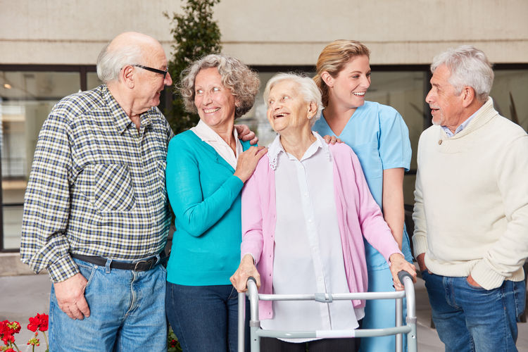 Smiling nurse with senior people standing at nursing home