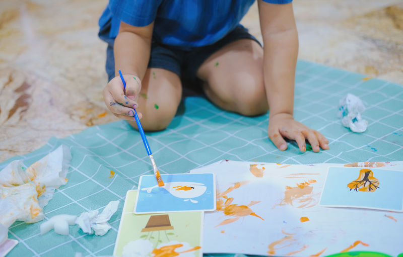 High angle view of boy playing with paper on table