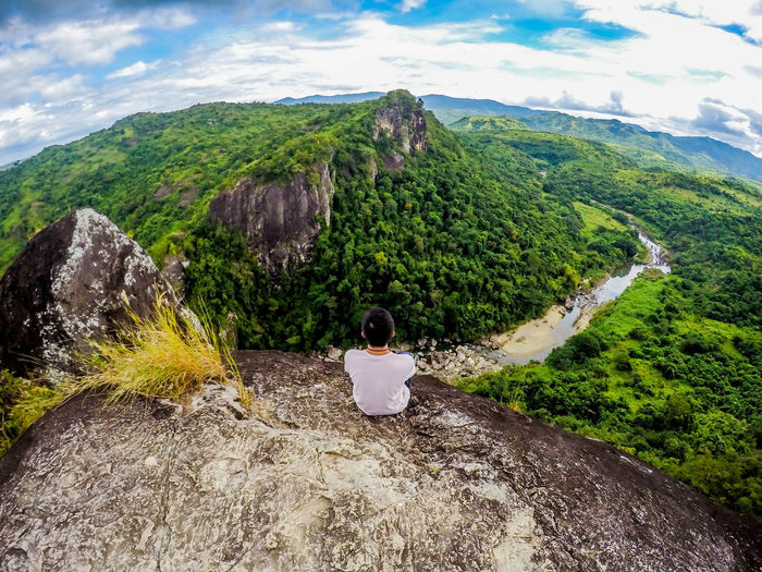 High angle view of woman sitting on mountain against sky