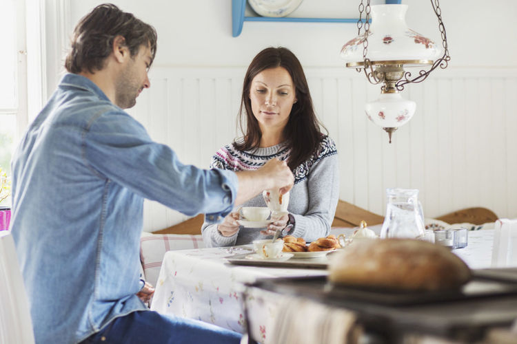Happy man serving coffee for woman at breakfast table