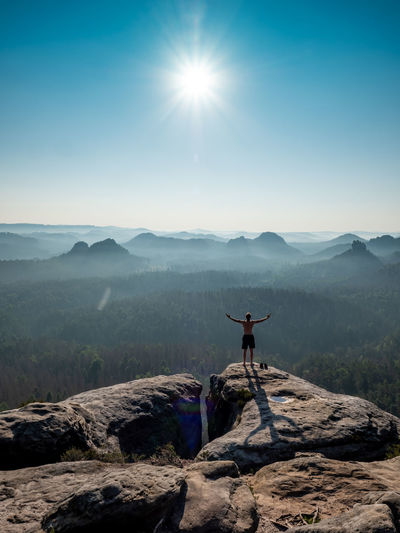 Shirtless male silhouette with raised arms on sharp mountain top. sport life and outdoor activities