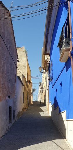 Narrow alley amidst buildings against blue sky