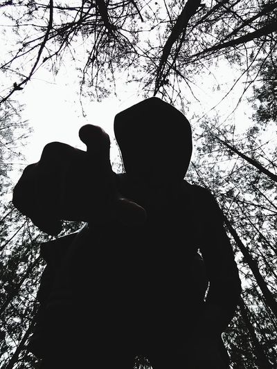 Rear view of silhouette man and woman standing by tree against sky