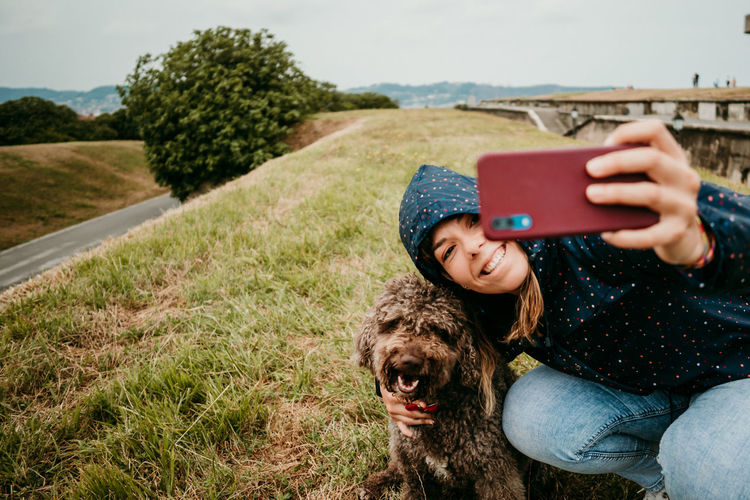 Woman taking selfie with dog on field