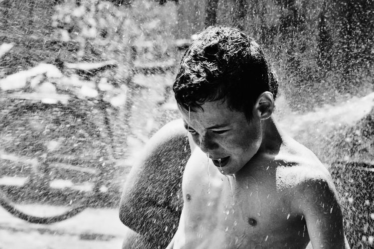 Shirtless boy playing in splashing water