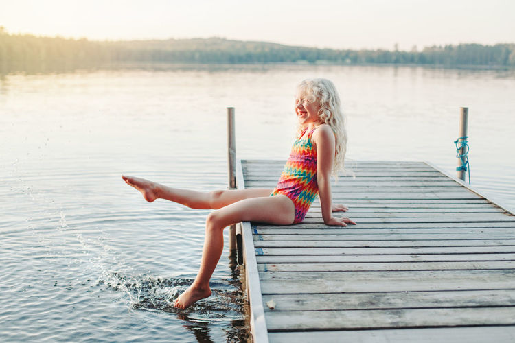 Full length of woman sitting on pier over lake