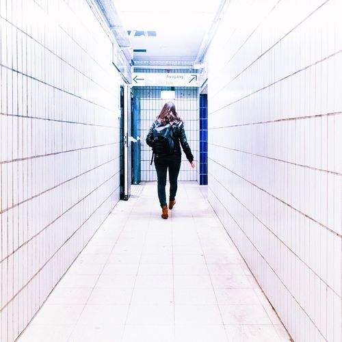 Rear view of woman walking in subway corridor