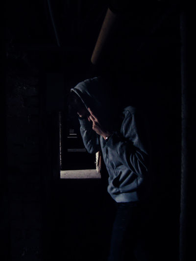 Man wearing hood standing in abandoned building