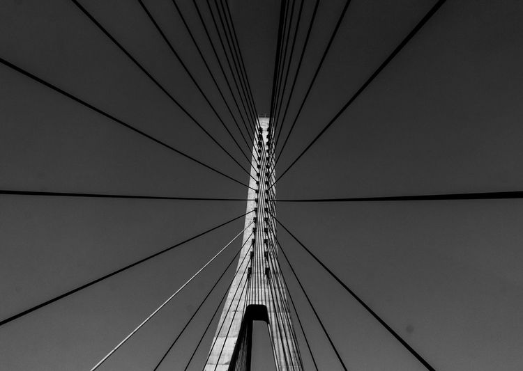 Low angle view of suspension bridge cables against sky