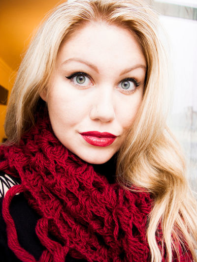 Portrait of beautiful young woman wearing maroon knitted scarf