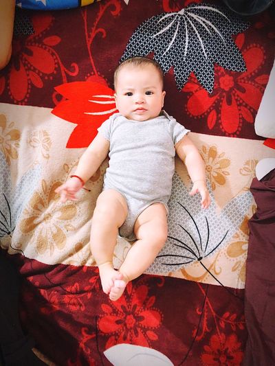 High angle portrait of cute baby boy lying on bed