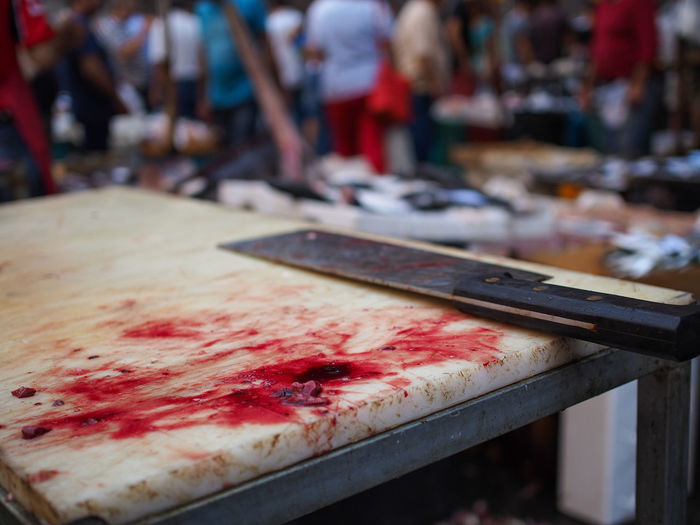 Close-up of meat cleaver with blood on cutting board at fish market