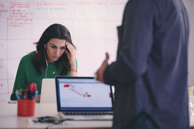 Tensed creative businesswoman using laptop at desk in office