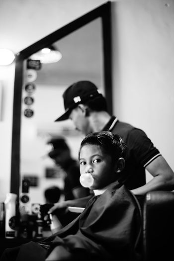Barber cutting hair of boy at barber shop