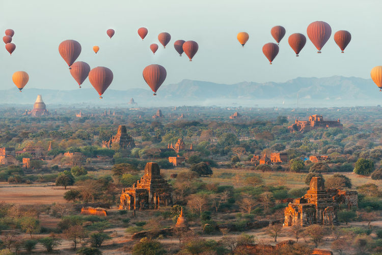 Hot air balloons flying over landscape against sky