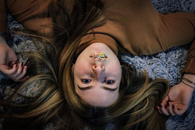 Directly above portrait of teenage girl with sprinkles on lips lying down